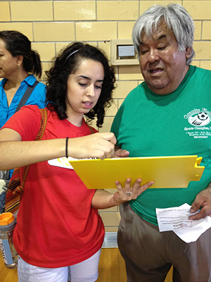 Sarahí helps a patient completing a cholesterol exam form