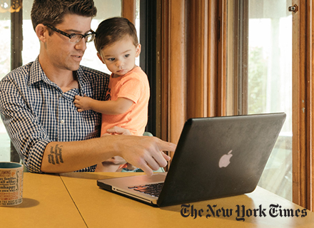 Photo of Zachary Turpin holding a child while pointing at laptop screen