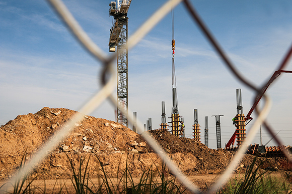 Concrete columns under construction behind a chain link fence