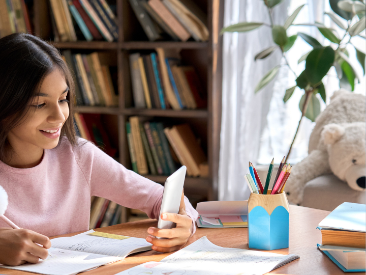 college aged girl talking on her phone while taking notes