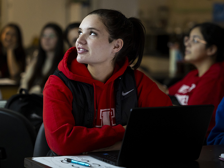 Female student in a red sweatshirt jacket sitting in class