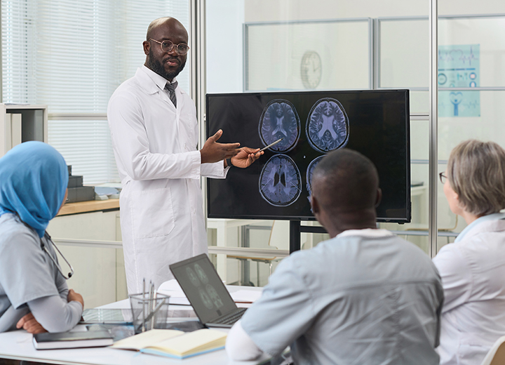 Black male doctor at a whiteboard teaching future medical students