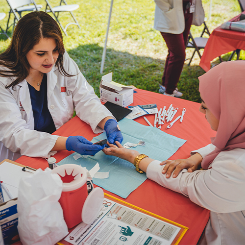 Pharmacy student measures blood glucose of patient