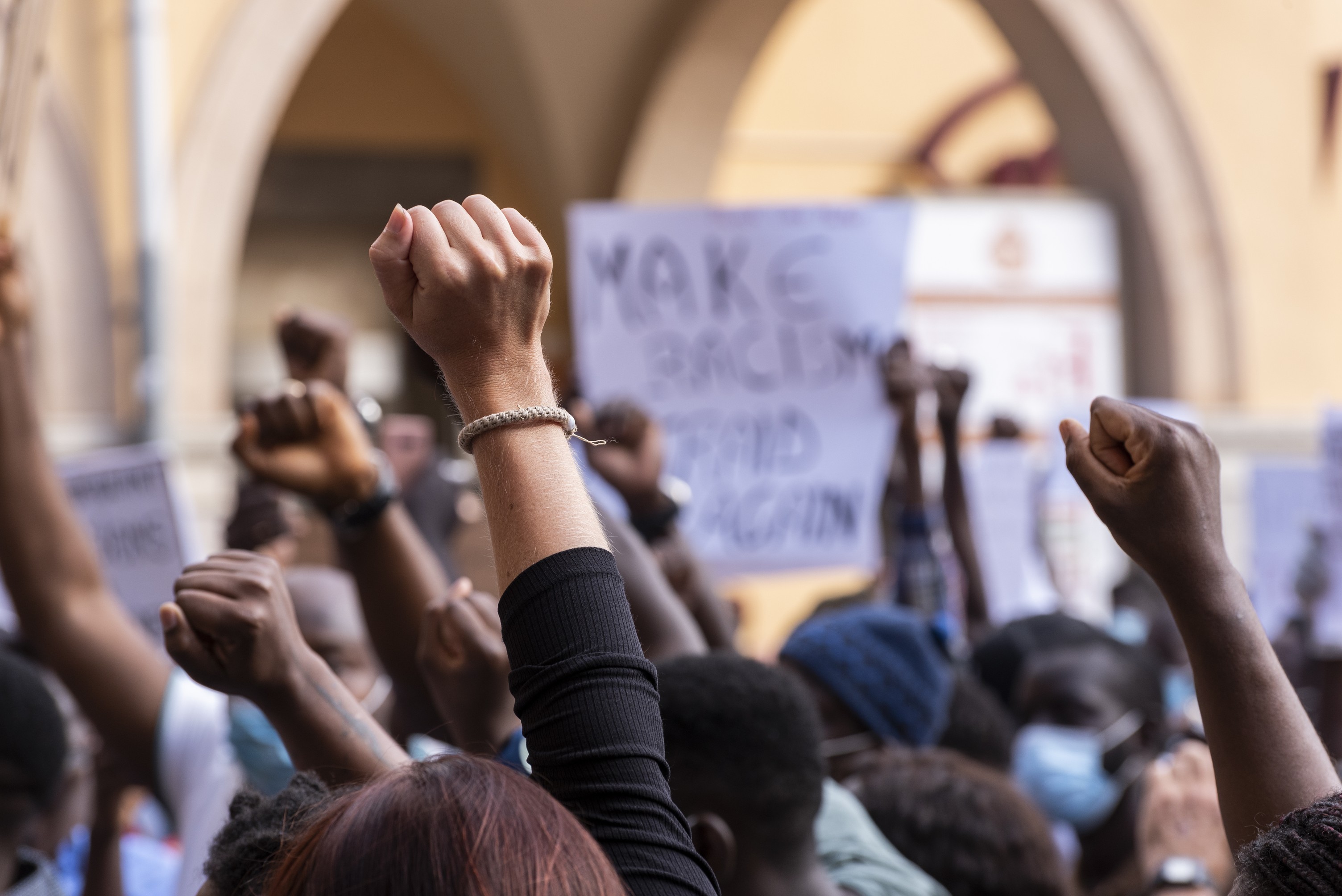 Wide shot of Anti-racism protesters raising their fists in solidarity Wide shot of Anti-racism protesters raising their fists in solidarity