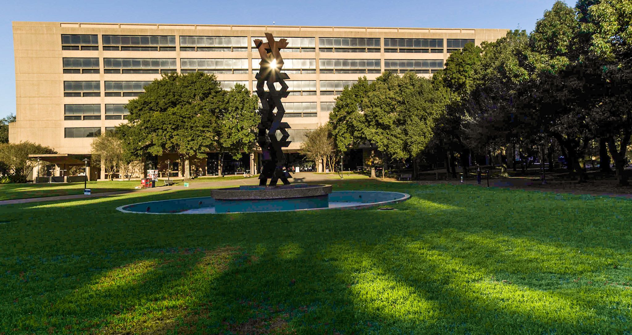 A picture of a fountain and metal sculpture in front of a building