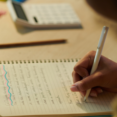 A student writes notes next to a calculator