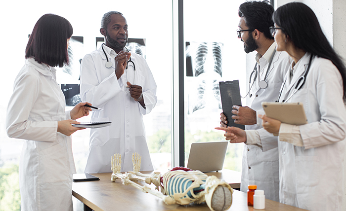 A group of male and female health professionals standing around a skeleton on a table