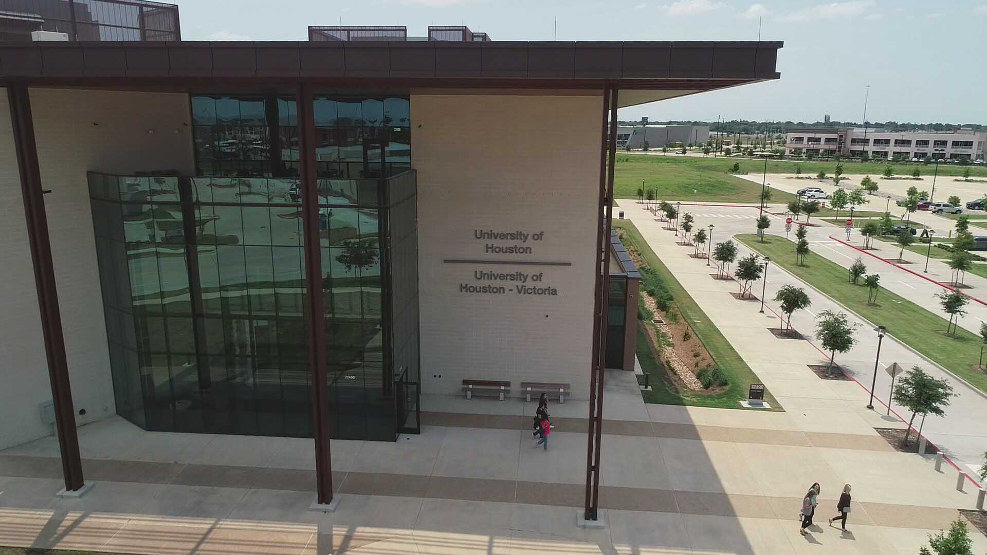 Landscape image of a three story building with light tan bricks and large windows. A sign is visible that says "University of Houston" and "University of Houston - Victoria".