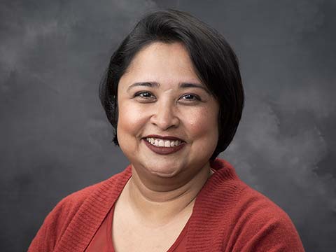 Portrait of an Indian woman with short hair smiling.