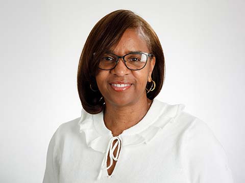 Portrait of a Black woman wearing a white blouse and glasses.