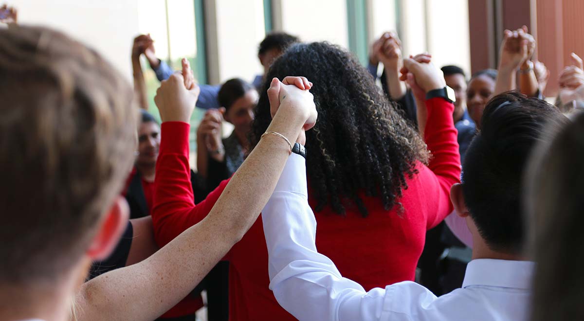 A group of people hold hands together with their arms raised high.