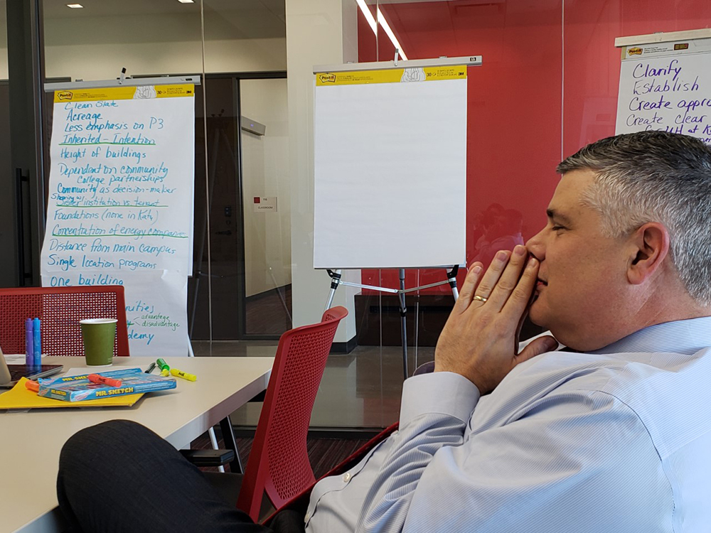 A man sitting at a table with paper flip charts in the background