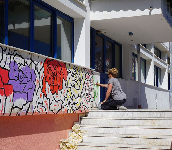 Tyler Kay painting floral mural in Greece
