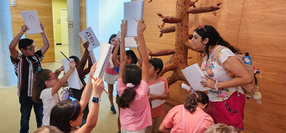 a teacher and elementary school students look at art at the University of Houston