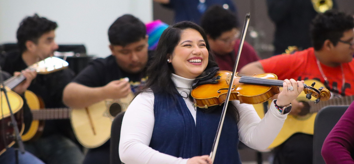 a violinist smiling at the 2023 community Mariachi Reunion hosted by the University of Houston Mariachi Pumas