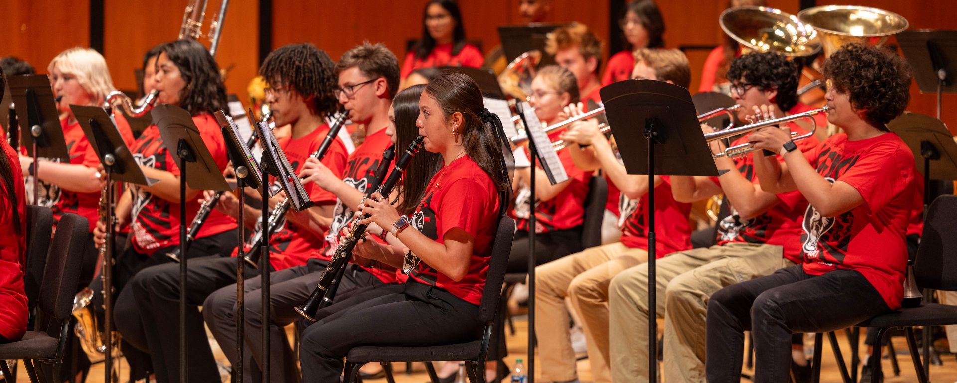High school woodwind and brass players performing in red shirts