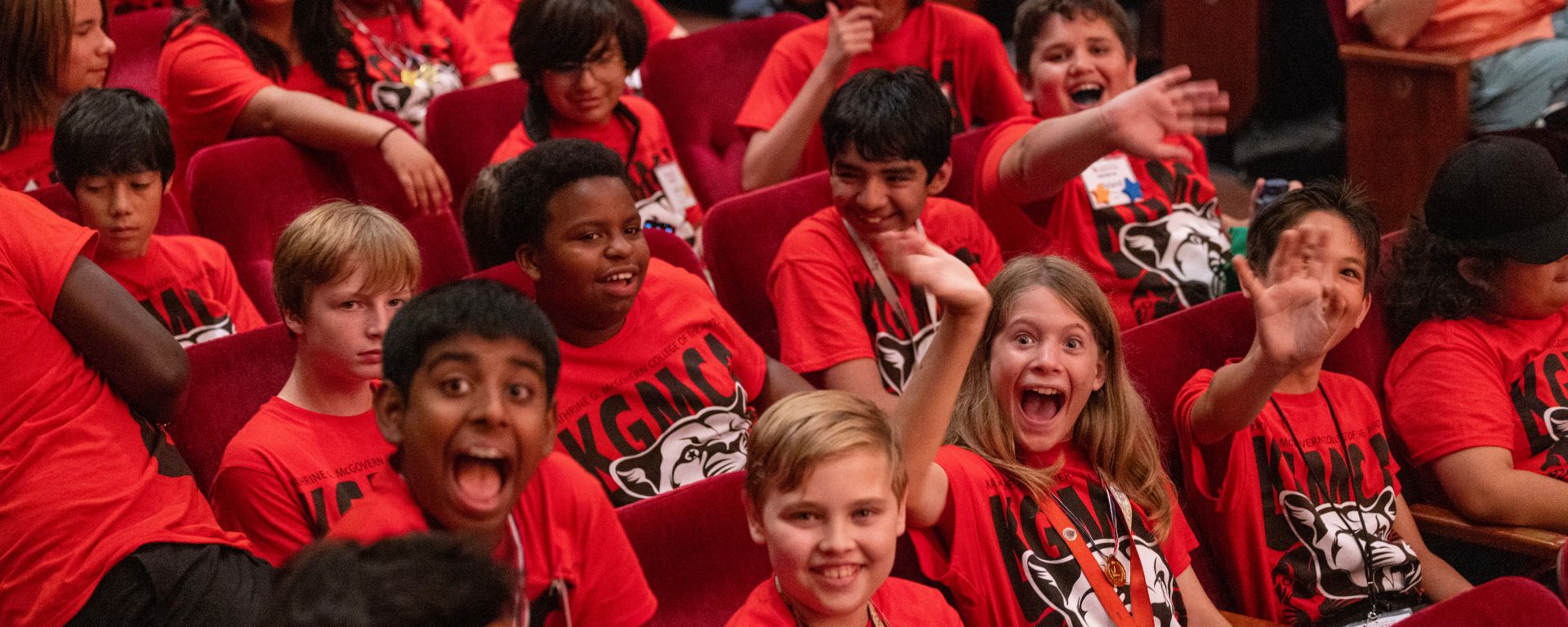 Smiling and waving middle school band students in red KGMCA shirts