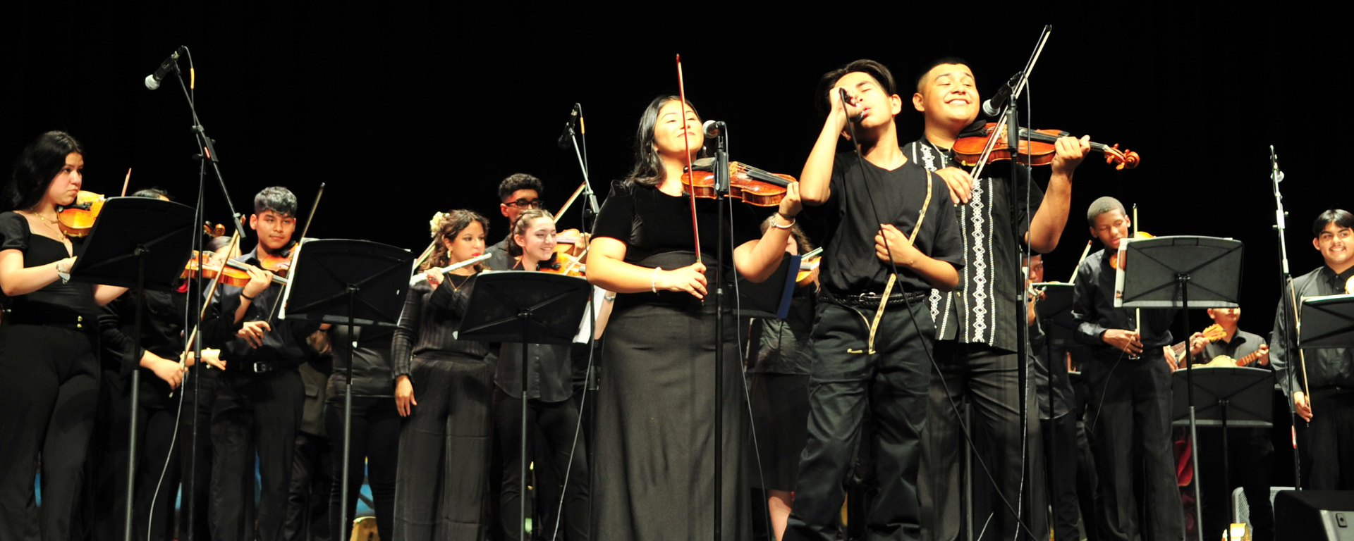 High school mariachi group in black smiling and singing