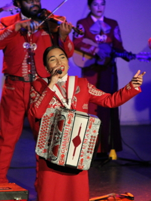 a mariachi accordion player in red singing a song
