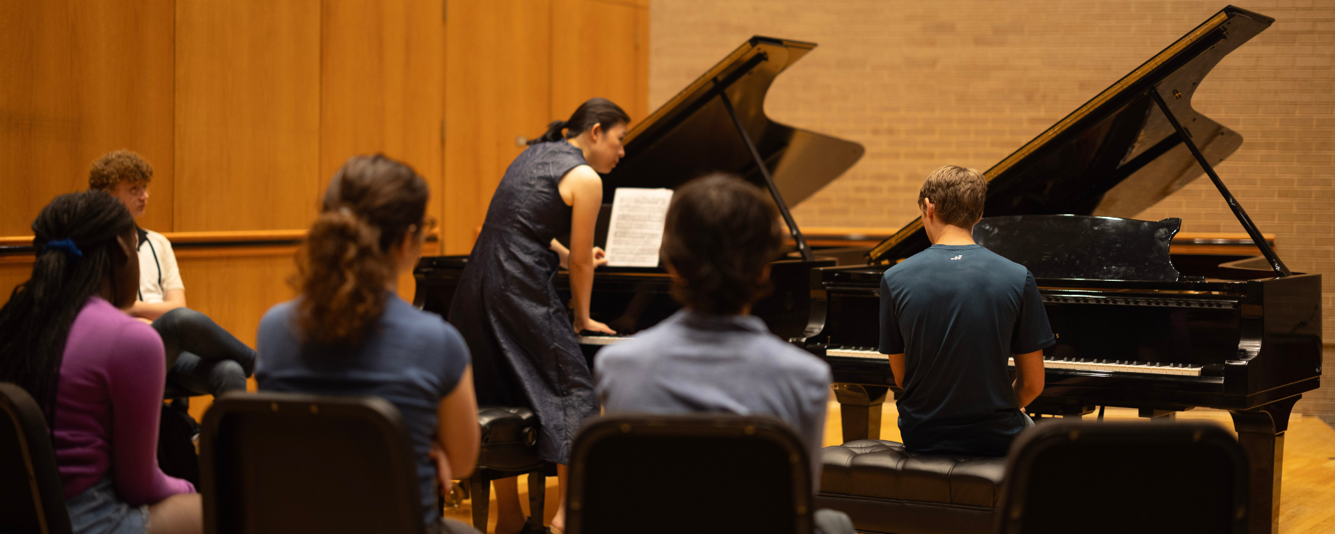 A group of young pianists watching a piano masterclass