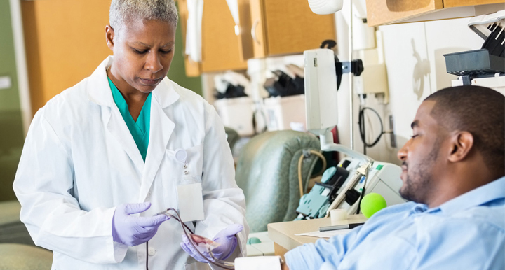 Medical doctor with a patient, looking electronics