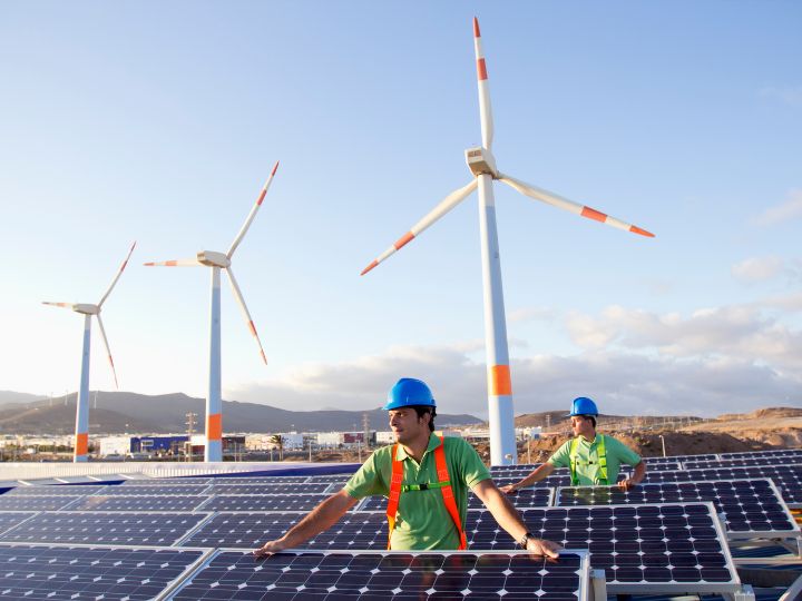 Worker with solar panels and wind turbines Worker with solar panels and wind turbines