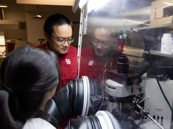 As Professor Xiaonan Shan observes, UH graduate Guangxia Feng works on the operando reflection interference microscope (RIM) inside a “glove box.” 