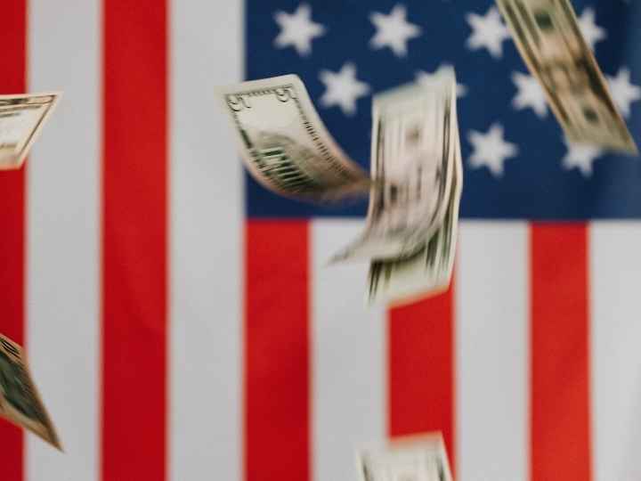 Photo showing dollars falling in front of American flag Photo showing dollars falling in front of American flag