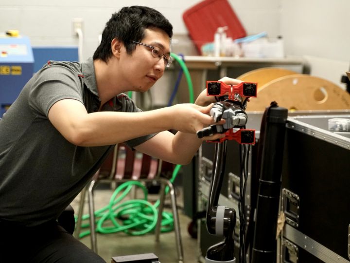 Wenyu Zou mounting a camera on a robotic arm at a University of Houston lab.