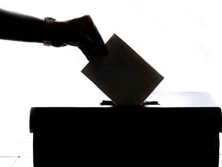 Photo showing person’s hand dropping ballot into voting box Photo showing person’s hand dropping ballot into voting box