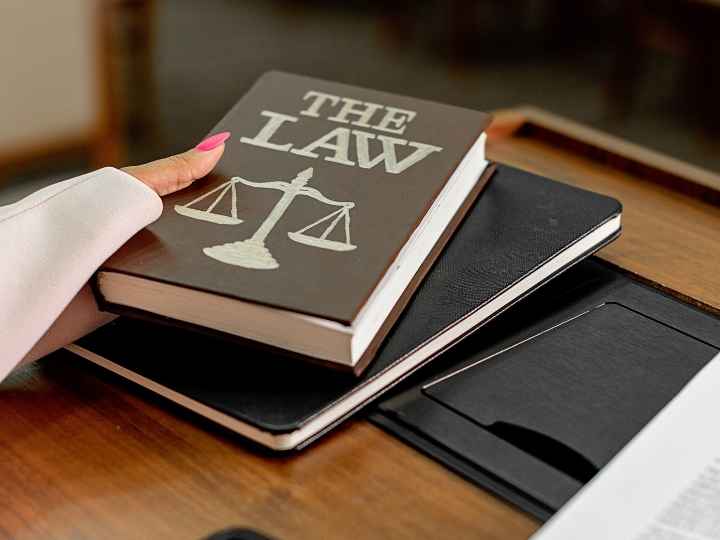 Photo of woman’s hand holding a law book Photo of woman’s hand holding a law book