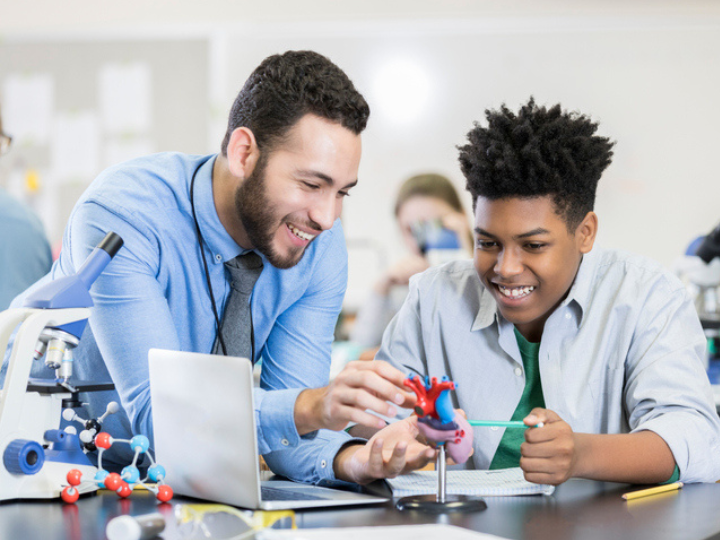 Photo of teacher guiding student in science experiment Photo of teacher guiding student in science experiment