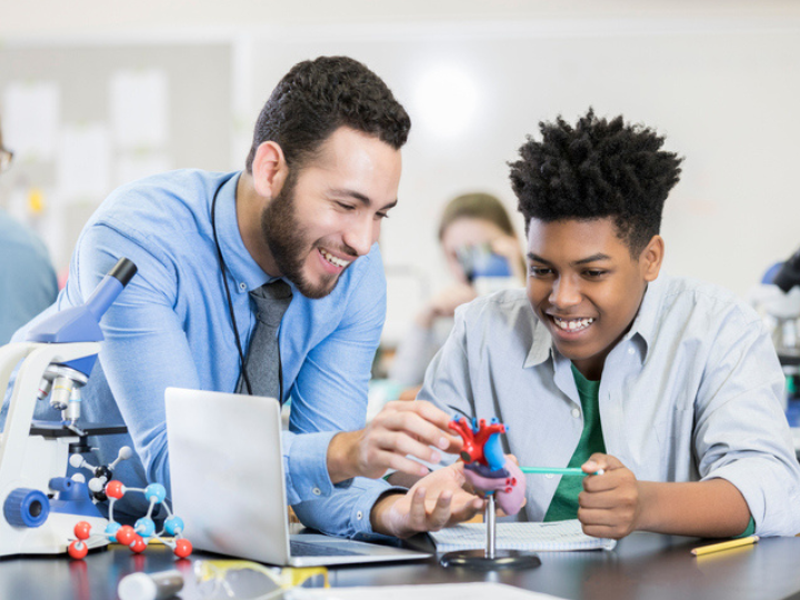 Photo of teacher guiding student in science experiment