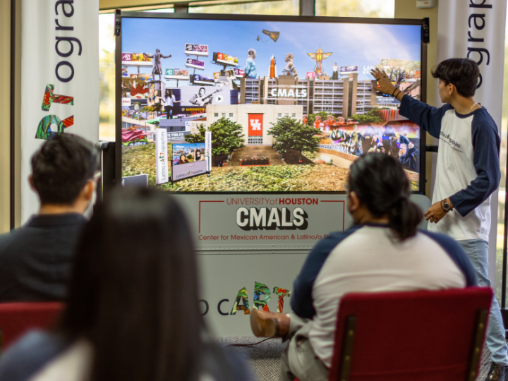 member of the CMALS team demonstrates the Latino cARTographies board to a small crowd