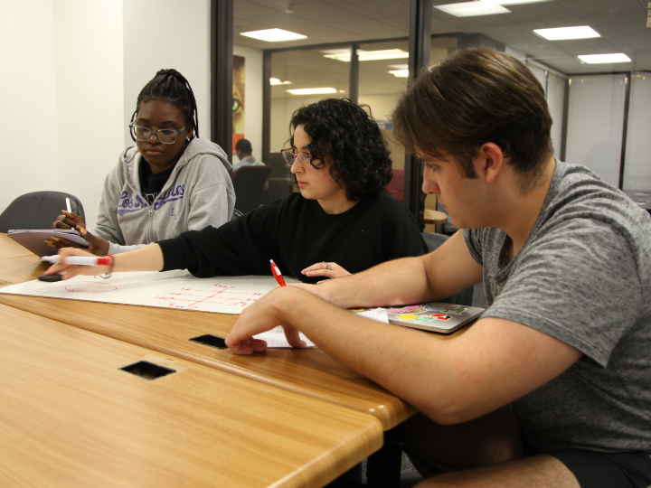 Three students work on school work at a table