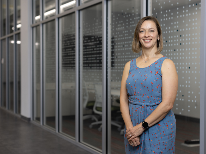 Professor Anny Castilla Earls stands in front of a clear wall