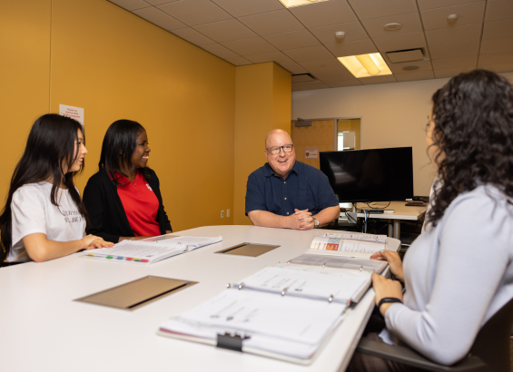 Jeremy Miciak sitting at a table with three students