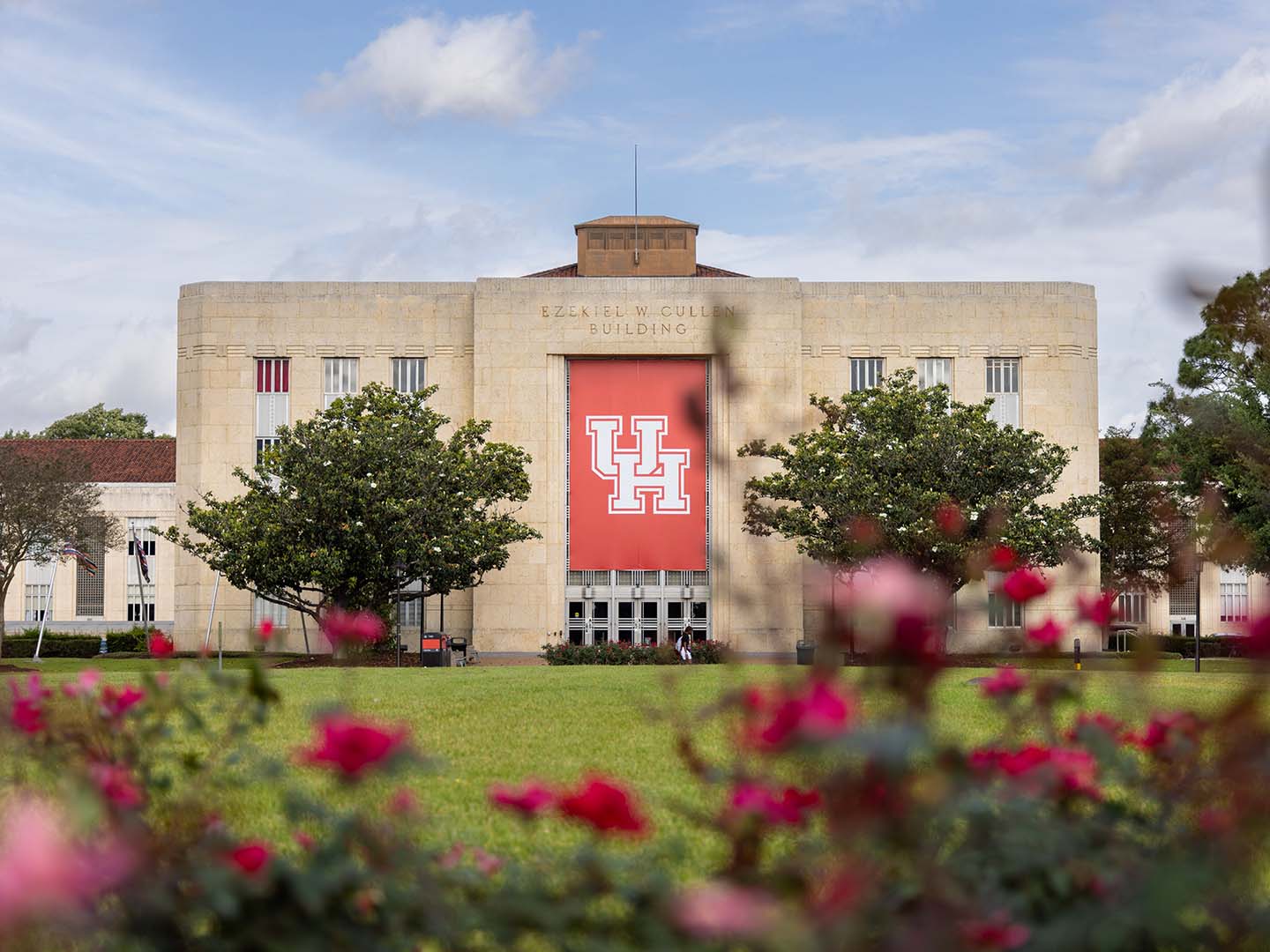 Cullen Performance Hall at the University of Houston with a large red UH banner and blue skies.