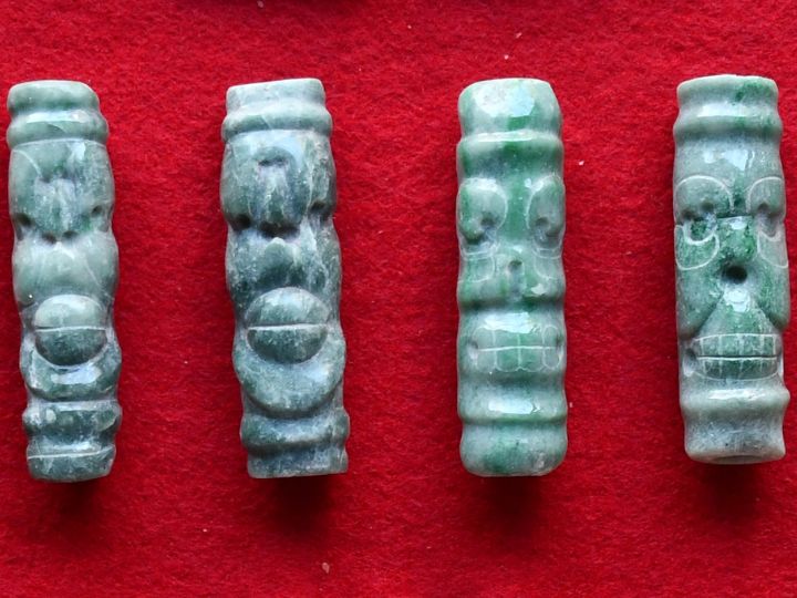 Four jadeite tubular beads showing live and dead spider monkeys