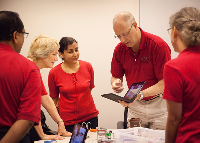 STEP participants discuss innovative physics iPad apps with Nancy Kralik (left), whose family provided funds for two high school teachers to attend the program. iPad applications are one of many activities participants learned about to reach students in new ways.