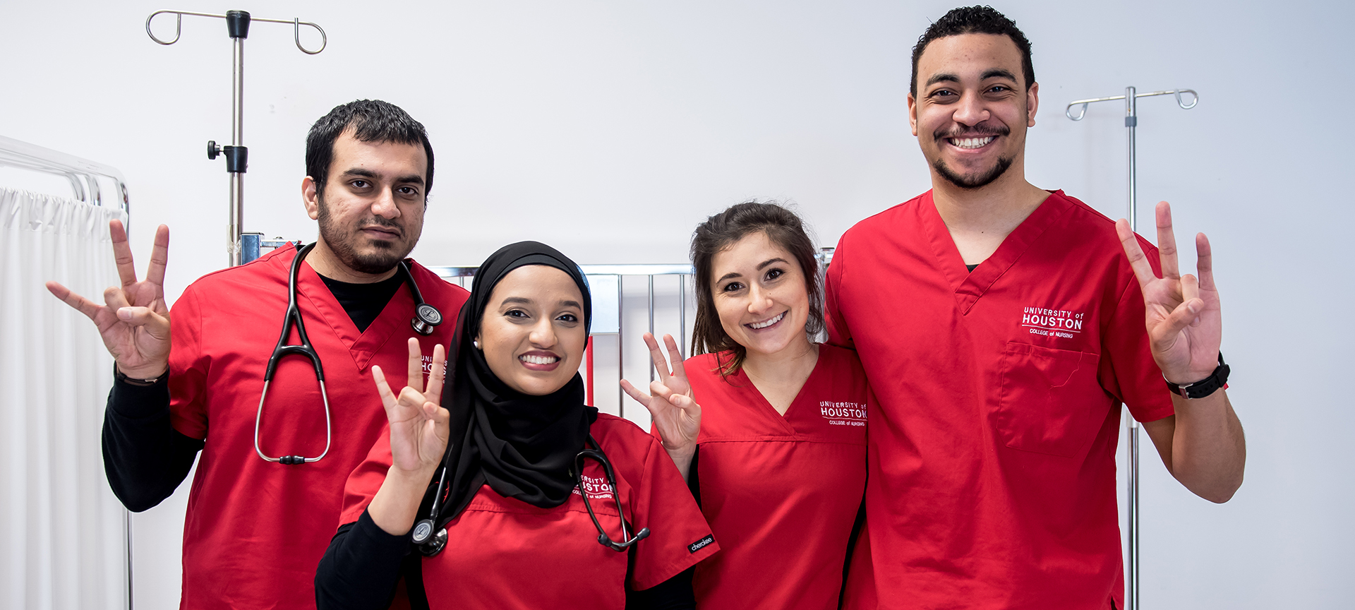 Five nursing students standing together making Go Coog handsign