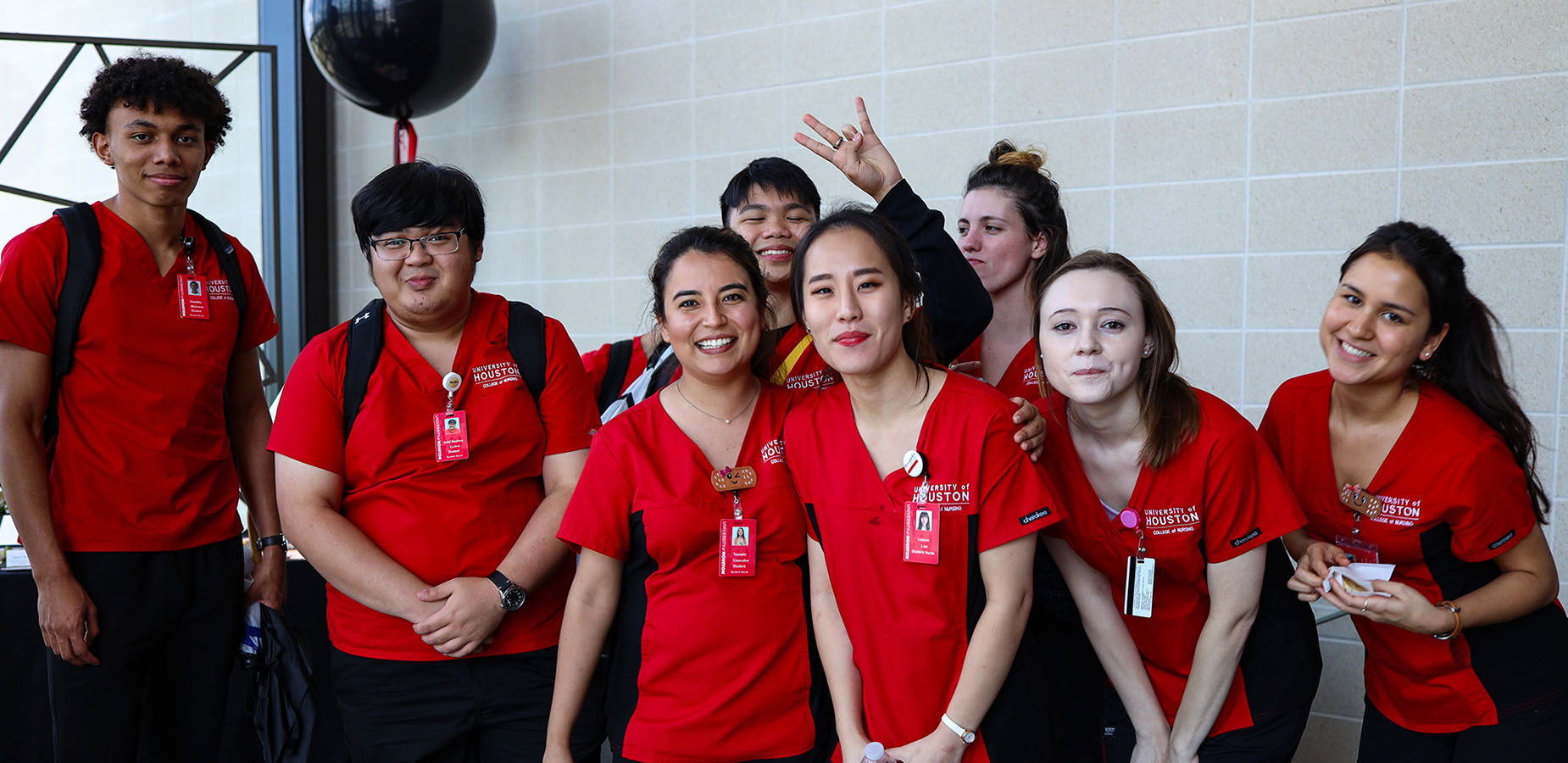 College of Nursing students wearing red scrubs standing together in a lobby