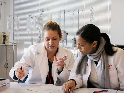 Two nursing faculty sit at a desk reviewing papers.