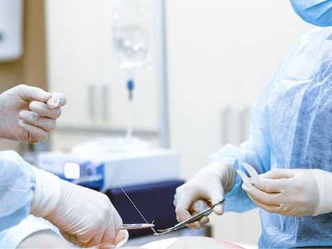 Two people in surgical scrubs perform surgery