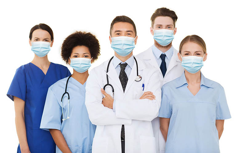 A group of male and female healthcare workers wearing maskes. Some are wearing scrubs and the rest are wearing labcots.