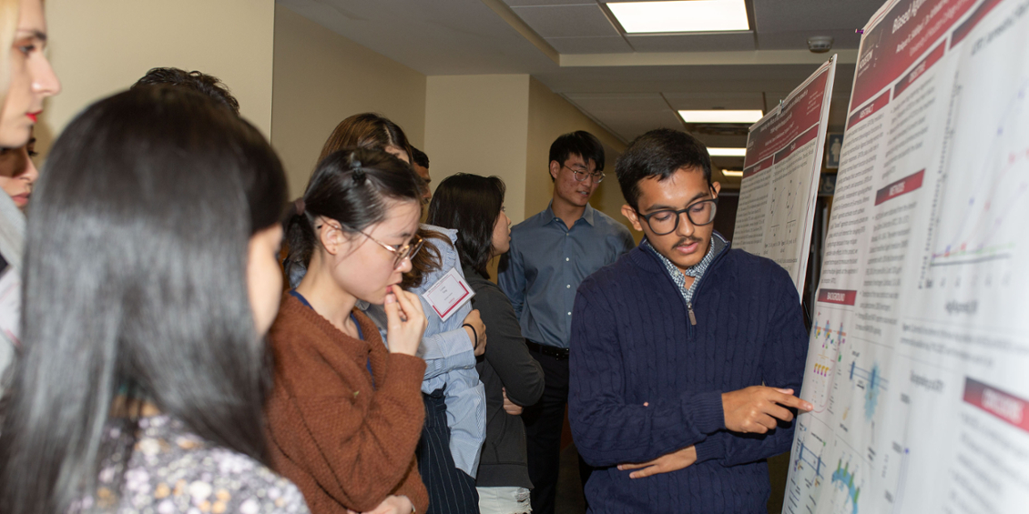 Student discusses poster with attendee