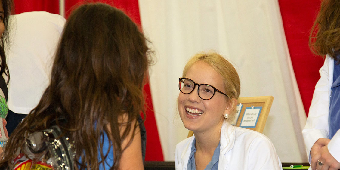 Pharmacy student interacts with young girl at the health education displays.