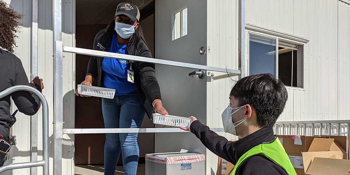 student transports covid vaccine tray