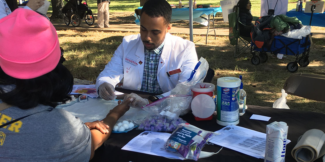 student performs wellness screening at event