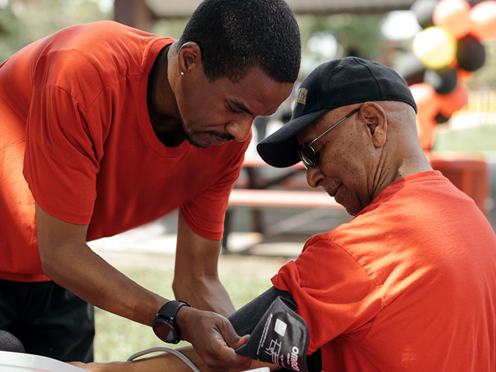 Ezemenari Obasi checking blood pressure at community health fair. Photo credit Todd Spoth.